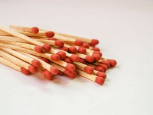 Haufen hölzerner Streichhölzer mit roten Zündköpfen auf weißem Untergrund
